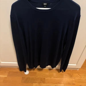 Blå stickad tröja från Uniqlo - Snygg mörkblå stickad tröja från Uniqlo i storlek L men sitter bättre på M.Tillverkad i 100% ull pris är förhandlingsbart och bara skriva vid frågor eller funderingar.