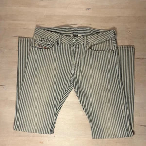 Randiga jeans från Diesel  - Snygga jeans från Diesel Industry med blå och vita vertikala ränder. Klassisk femficksmodell med detaljerade sömmar och logotyp på myntfickan. Tillverkade i 100% bomull för en skön känsla. Perfekt för dig som vill sticka ut med en unik look.