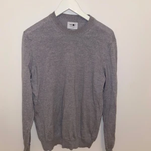 Grå stickad tröja från NN07 - Snygg grå stickad tröja från NN07 med rund halsringning och långa ärmar. Perfekt för lager-på-lager och enkel att matcha med jeans eller chinos. Mjuk och skön känsla tack vare det stickade materialet.