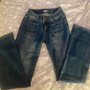 Jeans från Madlady - Snygga blå jeans från Madlady med bootcut passform och mid waist. Jeansen har framfickor med markerade sömmar, dubbla knappar i midjan och bakfickor med lock och knapp. Nästan helt oanvända. Orginalpris, 700