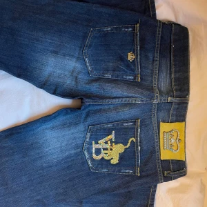 Tuffa Victoria Beckham  jeans med paljettdetaljer - Mörkblå lågmidjadejeans från Victoria Beckham, modell 126, med ikonisk guldfärgad krona på bakfickan och många snygga detaljer❣️De är vintage men i nyskick, pris kan diskuteras. 