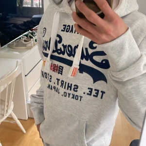 Superdry Vintage hoodie (Nyskick) - Säljer nu denna riktigt snygga Superdry hoodie i Storlek M med ett sjukt snyggt tryck och stilrena detaljer! Passar perfekt till höst och vinter och passar det mesta🤩 Skriv vid funderingar 🤝 Tröjan tillverkas ej längre och är eftertraktad 🙌