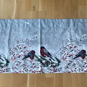 En väldigt julig och fin gardinkappa - En väldigt fin gardinkappa med vintermotiv, röda bär och domherrar. Jag säljer en väldigt julig och fin gardinkappa. Köpte denna gardinkappa förra året men kom aldrig till användning och den är nu för kort i vårt fönster. Köpt på meter. Ger en väldigt julig känsla. Mått: Bredd: 199,5cm cm och längden är 45,5cm