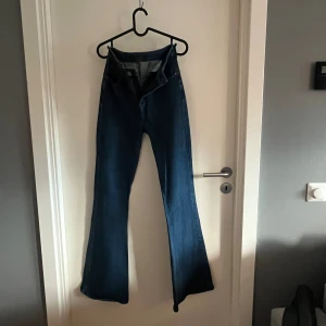 Lee Super High Flare jeans blå - Blå jeans från Lee med superhög midja och riktigt utsvängda ben. Modellen heter Super High Flare och har klassiska fickor både fram och bak. Jeansen är gjorda i ett mjukt denimtyg som sitter bekvämt. 