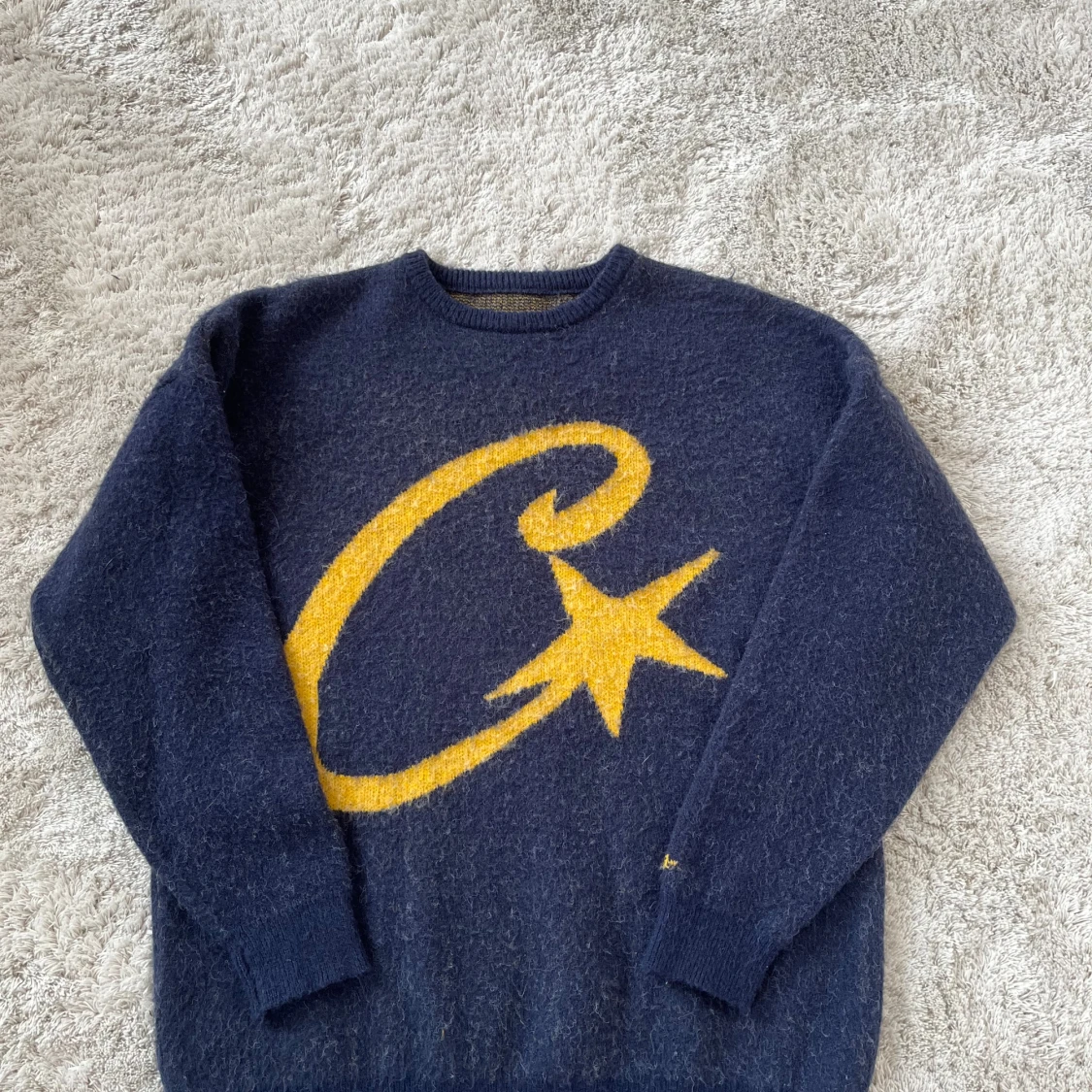 Mörkblå stickad tröja med gul stjärna från Corteiz