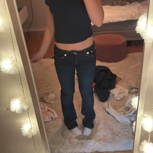 Mörkblå True Religion jeans mid waist - Säljer ett par mörkblå jeans från True Religion med mid waist, de är lite bootcut men sitter väldigt bra,om man vill ha de lite mer lågmidjade är det bara att dra ner de lite.