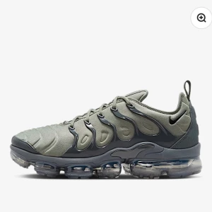 Nike Air Vapormax Plus grå sneakers - Nike Air Vapormax Plus sneakers i en snygg grå färg med futuristisk design. Ovandel i syntet och mesh med coola vågformade detaljer och snörning. Sulan är genomskinlig och ger en unik look samt grym komfort. Perfekta för dig som vill sticka ut med dina sneakers.