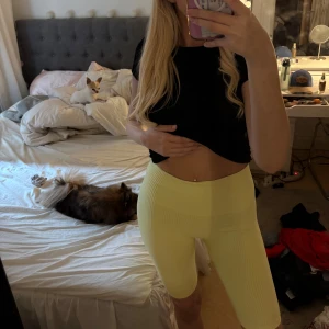 Gula ribbade cykelshorts från Röhnisch - Säljer ett par ljusgula cykelshorts från Röhnisch med ribbad struktur och hög midja. De är stretchiga och sitter tight, perfekta för träning eller chill. Materialet är mjukt och följsamt syntet. Röhnisch-loggan syns på bakre linningen.