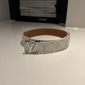 Vitt bälte med mönster och silverfärgat spänne - Säljer ett Vit bälte storlek 110cm. I helt nytt skick. Säljer den eftersom jag inte har något behov för den längre. 