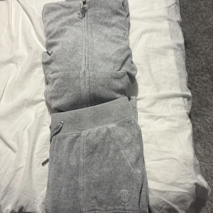 Grå hoodie med dragkedja från Juicy Couture - Grå hoodie från Juicy Couture och byxorna storlek XS på båda använda några gånger men är i bra skick säljs biligt som ett paket pris pga att dom inte kommer till användning💗