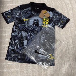 Nike Brasil CBF svart/grå fotbollströja - Snygg Brasilien CBF fotbollströja från Nike med unikt svart och grått grafiskt mönster, gult broderat klubbmärke och Nike-logga. Tillverkad i Dri-FIT material som andas. Kortärmad modell med rund hals och coola detaljer inspirerade av Rio.