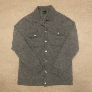 Grå Massimo dutti Kashmir cardigan/overshirt - Mysig grå kofta från Massimo Dutti i en lyxig mix av ull och kashmir. Klassisk design med krage, knäppning framtill och två bröstfickor med lock. Perfekt för lager-på-lager och en clean look.står stolen M men sitter som S/XS