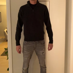 Mörkgrå stickad half zip-tröja Uniqlo - Passar M/L! Mörkgrå stickad tröja från Uniqlo i storlek S. Tröjan har en hög krage med half zip-dragkedja och är ribbstickad för en snygg struktur. Perfekt för kyliga dagar och enkel att styla med jeans eller chinos.