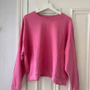 Rosa sweatshirt med loose fit - En chill rosa sweatshirt med loose passform och rund hals. Tröjan har långa ärmar och är tillverkad i mjuk bomull, perfekt för att slänga på sig när man vill vara bekväm. Enkel design utan mönster eller detaljer, passar dig som gillar stilrena vibes.