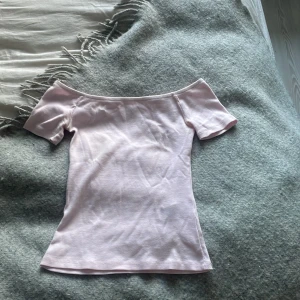 Ljusrosa offshoulder topp - Säljer en ljusrosa offshoulder topp med korta ärmar. Toppen har en slim passform och är tillverkad i mjuk bomull som känns skön mot huden. Perfekt för dig som gillar en enkel och stilren look med en feminin touch.