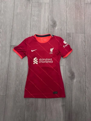 Röd Liverpool matchtröja  - Tja den är i mycket bra skick i storlek Xs/xxs från Liverpool. Den är i storlek Xs men den är som compression fit och sitte ridåer tajt för Xs. Den är authentisk