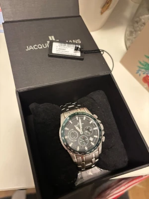 JACQUE LEMANS Klocka - Bilderna visar en klocka från Jacques Lemans i originalask med extra länkar, Sparsamt använd och som ny. Jag har förkortat den och tagit bort  2 länkar men dem tillkommer. Tveka inte på o ställa frågor🤗