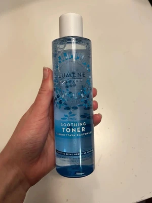 Lumene Soothing Toner 200ml - Lumene Soothing Toner är en ansiktsvatten för känslig hud, med en fräsch blå design och vit kork. Innehåller nordiskt källvatten och är parfymfri. Flaskan är gjord av plast och rymmer 200 ml. Perfekt för att återfukta och lugna huden efter rengöring.