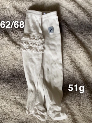 Vita mjuka byxor med volangdetalj - Supersöta vita byxor från Polarn O. Pyret. Byxorna har inbyggda fötter och fina volangdetaljer på benen. Perfekta för mysiga dagar hemma eller när du vill ha något gulligt och bekvämt till de minsta.🌸Fint använt skick ( har två likadana, säljs var för sig ) storlek 62/68