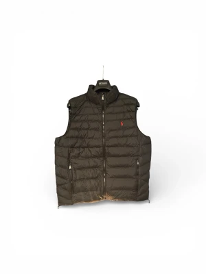 Svart dunväst från Polo Ralph Lauren - Svart dunväst från Polo Ralph Lauren med röd broderad logga på bröstet. Västen har quiltad design, dragkedja framtill och två sidofickor med dragkedja. Perfekt för lager-på-lager och har en stilren look med hög krage.