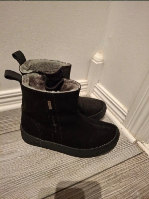 Svarta fodrade boots från Canada snow - Säljer ett par svarta boots från Canada snow med grov sula och dragkedja på sidan. Skorna är fodrade med mjuk päls på insidan och har en ovandel i mocka. Perfekta för kalla vinterdagar och har rejäla gummisulor med bra grepp.