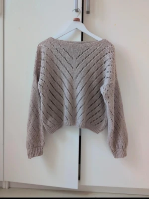 Beige stickad tröja Copenhagen Luxe - Säljer en beige stickad tröja från Copenhagen Luxe med snyggt hålmönster i V-form. Tröjan har långärmade ärmar med ribbade muddar och en loose passform som ger en chill vibe. Perfekt att slänga på sig under hösten eller vintern.