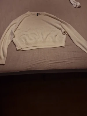 Beige croppad stickad tröja Divided - Säljer en beige  stickad tröja från Divided (H&M). Tröjan har lång ärm, rund halsringning och ribbade muddar vid ärmslut och nederkant. Perfekt för lager på lager under höst och vår. Säljer för 150, priset kan diskuterats