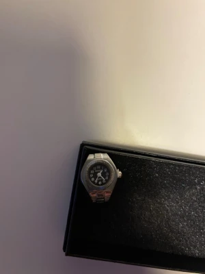 silvrig ringklocka - En silver ring med inbyggd klocka. Passar till alla tillfällen, stilren och oanvänd. Justerbar storlek.