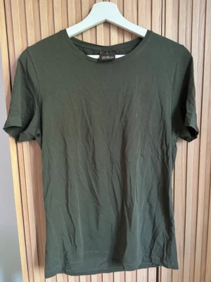 Oscar Jacobson  t-shirt - En enkel mörkgrön t-shirt från Oscar Jacobson med rund hals och korta ärmar. Tillverkad i mjuk bomull som känns skön mot huden. Perfekt till jeans eller shorts för en clean och avslappnad look.