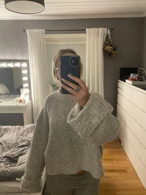 ljusgrå stickad tröja från Gina Tricot - supermysig ljusgrå stickad tröja från Gina Tricot i oversized modell. tröjan har breda ärmar och en högre rund halsringning. 