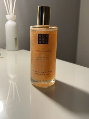 Rituals The Ritual of Karma Shimmering Body Oil - Shimmering body oil från Rituals, The Ritual of Karma. Oljan har en varm gyllene ton med skimrande effekt och doft av lotusblomma och vitt te. Perfekt för att ge huden extra glow.