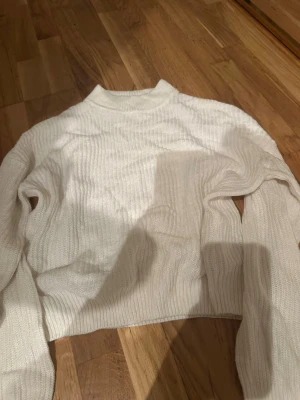 Vit ribbad stickad tröja FB Sister - Säljer en vit stickad tröja från FB Sister i storlek S. Tröjan har ribbad struktur, lång ärm och en lite högre hals. Perfekt för dig som gillar enkel och clean stil. Materialet är mjukt och skönt, passar bra till jeans eller kjol.