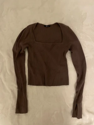 Brun ribbad topp från Gina Tricot - Säljer en brun långärmad topp från Gina Tricot med fyrkantig ringning. Toppen är ribbad och har en slim passform som sitter snyggt på kroppen. Materialet är mjukt och stretchigt, perfekt till jeans eller kjol!!😊 väldigt fin men kom aldrig till användning bara