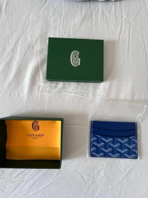 G-plånbok - Snygg och stilren i blå med deras ikoniska mönster. Plånboken har flera kortfack och är tillverkad i skinn med tryckt logga framtill. Perfekt för dig som vill ha något exklusivt och smidigt i fickan.  