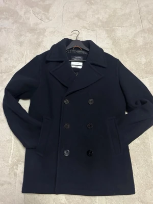 Mörkblå dubbelknäppt Rock  - Säljer en stilren mörkblå dubbelknäppt rock från Jack & Jones Premium. Varm och stilren så perfekt för dig som vill ha stil nu under vintern! 