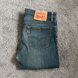 Levi's 510 skinny jeans blå - Snygga Levi's 510 jeans i klassisk blå tvätt med skinny passform. De har fem fickor, orange sömmar och den ikoniska röda Levi's-taggen vid bakfickan. Jeansen är tillverkade i slitstarkt denim och har en modern, smal siluett som sitter tajt hela vägen ner.