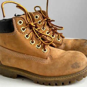 Timberland JR klassisk känga - Ett par klassiska Tilberland-kängor med bra och inte särkilt sliten sula. Dock är det bruna runt ankeln slitet och det finns märken på tårna. Håller dock vätan ute och funkar dessutom bra som vinterskor med en raggsocka i.