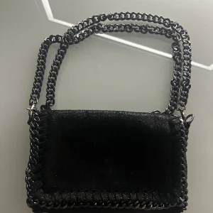 Svart axelväska med kedjedetaljer - Svart glittrig väska i äkta läder köpt i Spanien ❤️med avtagbar kedja kommer ej till användning ❤️