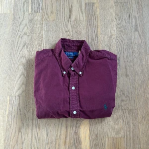 Ralph lauren skjort - Vin röd Ralph lauren skjorta med grön logga, perfekta färger inför julen eller fest. Fint skick utan några fläckar eller hål. Har du nån fråga är de bara att skriva.