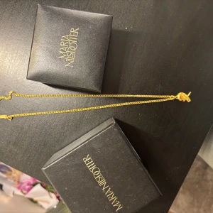 Guldigt halsband Maria Nilsdotter - Säljer mitt jätte fina  Maria Nilsdotter halsband för att jag tyvärr inte använder det längre. Kedjan är medelgrov och har en klassisk design som ger ett stilrent intryck. Perfekt för dig som gillar unika smycken med karaktär. Har tyvärr inte kvar kvittot  därför säljer jag den för ganska billigt. Jag betalade 2200 för den men kommer sälja den för 1000 . Har dock kvar orgenal boxarna som jag fick den med .