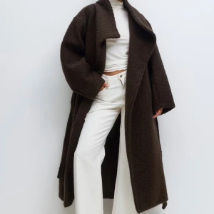 Mörkbrun teddyjacka med bälte - Säljer en oversized mörkbrun teddyjacka från Gina Tricot. Jackan har bred krage, långa ärmar och knyts med bälte i midjan. Perfekt för dig som gillar en mysig och trendig look med extra volym och längd. Väldigt bra skick som ny.