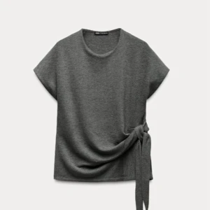 Grå topp med knyt i sidan - Säljer en grå super söt tröja från Zara. Har använts 2-3 gånger så den är i ett mycket bra skick. Den är i storlek L och  pris går att diskutera💕.