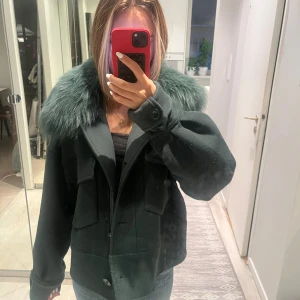 Mörkgrön jacka med päls från Meotine - Säljer en mörkgrön jacka från Meotine med stor fluffig päls-krage. Köpte för ungefär ett halvår sen för ca 2800kr. Den är lite nopprig men inte något man lägger märke till. Använder inte då den inte riktigt är min smak längre.