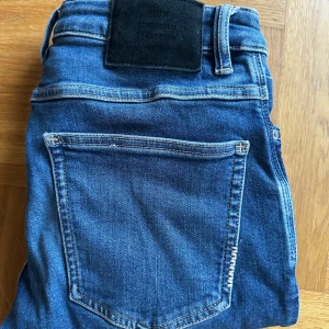 Blå slim fit jeans från Neuw - Snygga blå jeans från Neuw i modellen Lou Slim. Klassiska jeans med mörkblå tvätt tvätt. Jeansen har en slim passform och är tillverkade i ett väldigt skönt material.