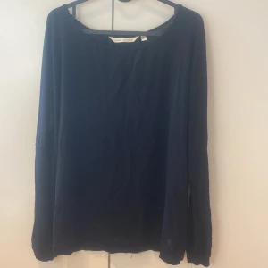 Svart långärmad tröja House of Lola - Snygg svart långärmad tröja från House of Lola i storlek XS. Tröjan har en bred rund halsringning och coola silverfärgade knappar längs hela ryggen. Tillverkad i mjuk bomull som känns skön mot huden. Perfekt för dig som gillar stilrena detaljer.