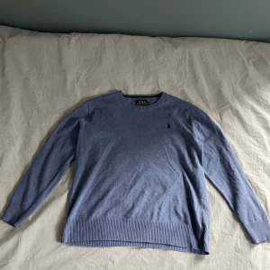 Blå tröja från Polo Ralph Lauren - Snygg blå tröja från Polo Ralph Lauren i mjuk pima bomull. Klassisk rund hals och ribbade muddar vid ärmslut och nederkant.  Skriv och fråga om du har några funderingar 