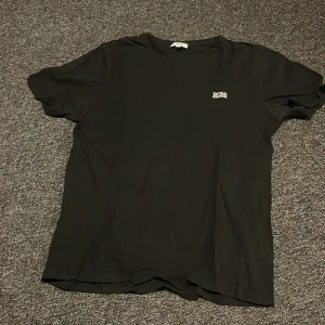 Svart t-shirt från BOSS - Svart t-shirt från BOSS med klassisk passform och diskret logga på bröstet. Tillverkad i mjuk bomull och har rund halsringning samt korta ärmar. Perfekt för en clean och stilren look.