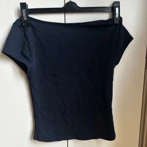 Marinblå tröja med öppen rygg från Gina tricot young  - Säljer en marinblå tight T-shirt från Gina Tricot young med korta ärmar och bred, öppen rygg. Aldrig använd, skriv om ni vill ha fler bilder på tröjan eller om ni vill se den på!🫶