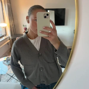 Brun kofta med stora knappar - Mysig brun kofta med v-ringning och tre stora knappar framtill. Koftan har två praktiska fickor och ribbade muddar vid ärmslut och nederkant. Perfekt för lager-på-lager och chill dagar.