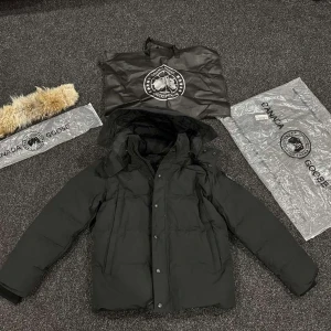 Svart dunjacka Canada Goose med päls - Svart dunjacka från Canada Goose med avtagbar huva och snygg pälsdetalj. Jackan har lång ärm, dragkedja och knappar framtill, samt logotyp på ärmen. Perfekt för kalla dagar med sin tjocka och quiltade design.